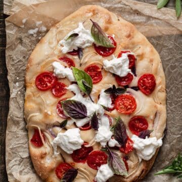 Focaccia with tomato, burrata and basil on top.