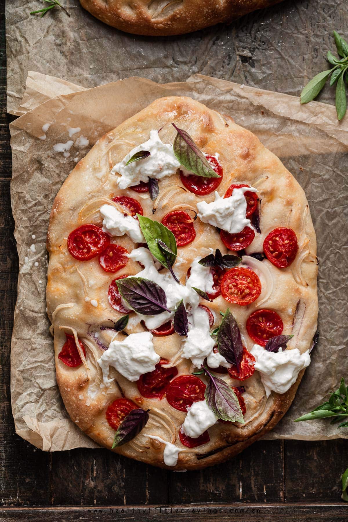 Focaccia with tomato, burrata and basil on top.