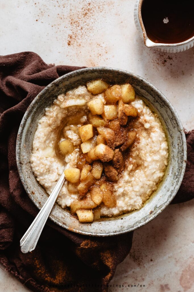 Apple oatmeal with cinnamon on top and a spoon inside the bowl