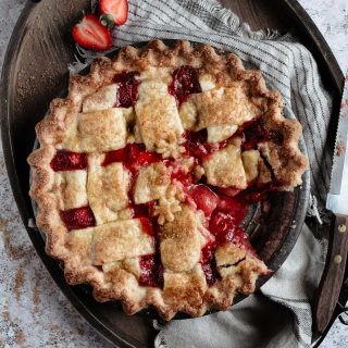 Strawberry pie with missing piece onto a wooden tray.