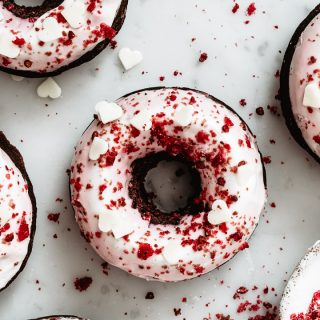 Close up of a red velvet donut with greek yogurt frosting and chocolate hearts on top