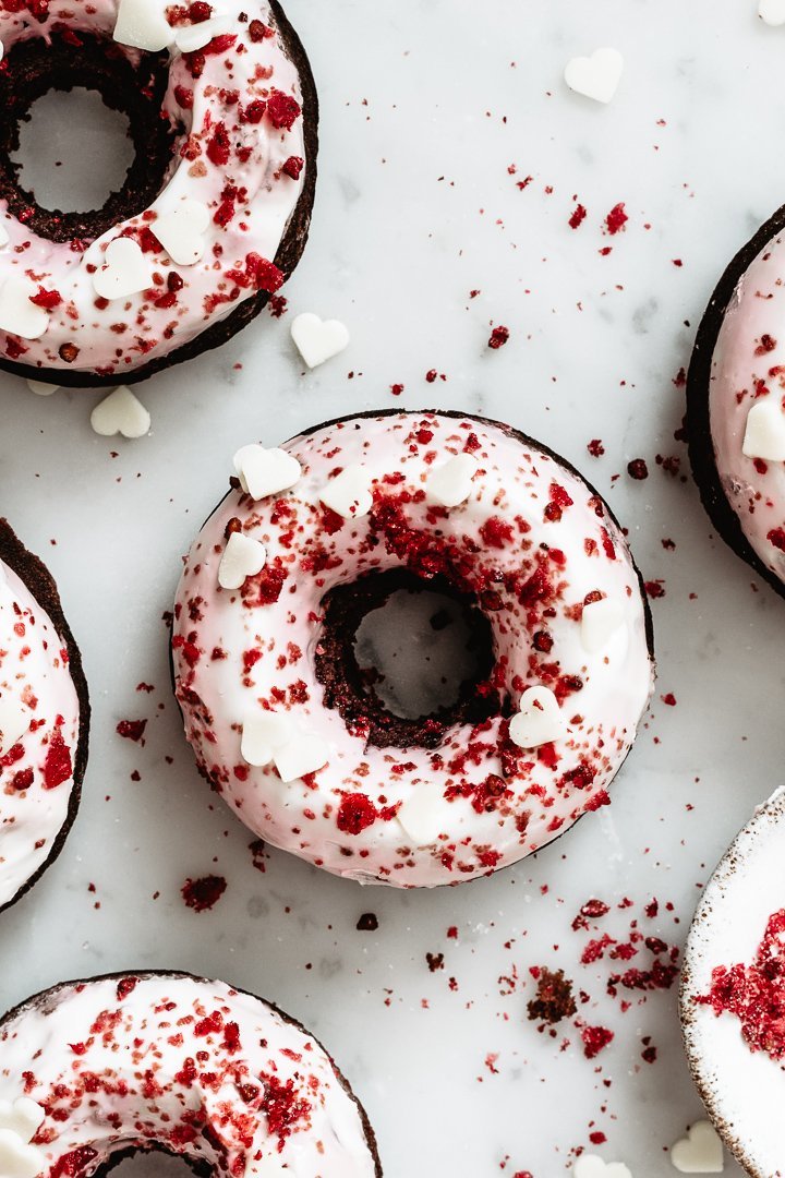 Close up of a red velvet donut with greek yogurt frosting and chocolate hearts on top