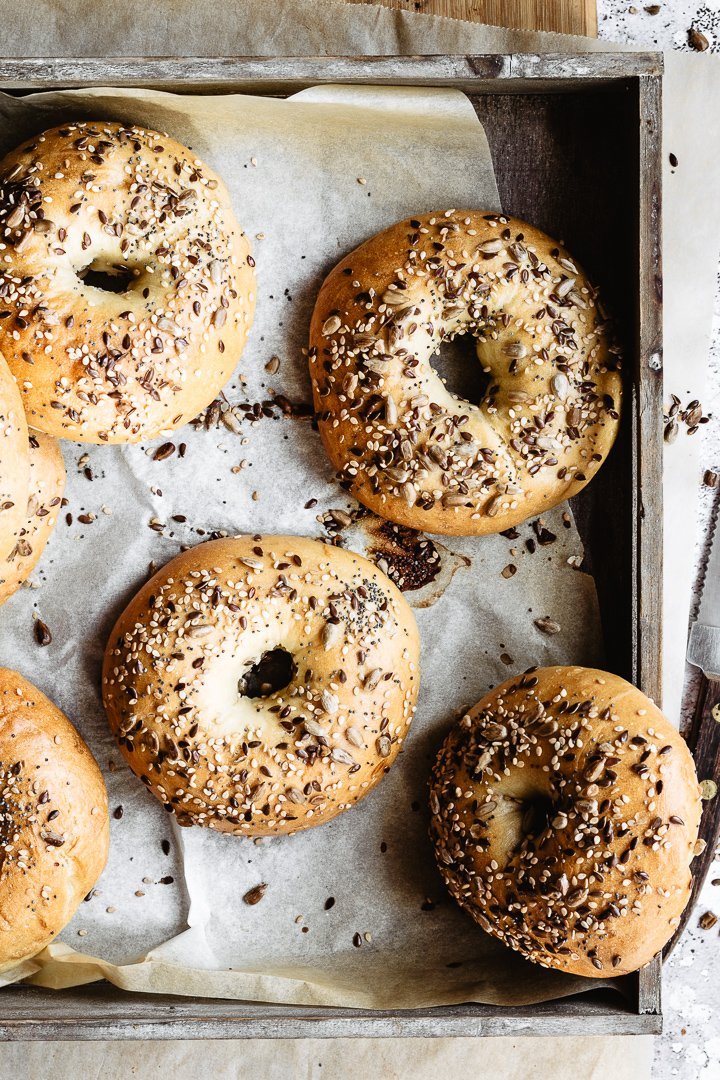 Multiple bagels on parchment paper inside a tray