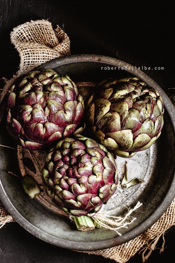 Raw globe artichokes onto a pan