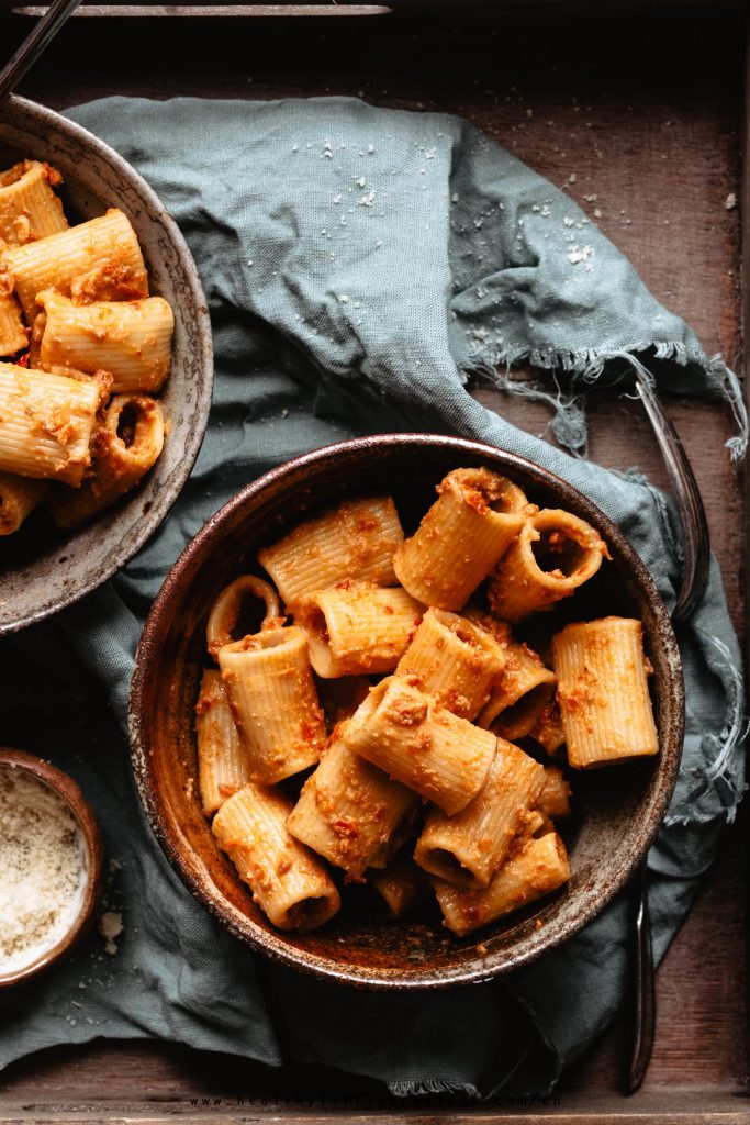 A sun dried tomato pesto pasta into a bowl on green napkin