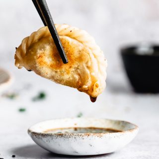 A single vegan potsticker dipped in its sauce.