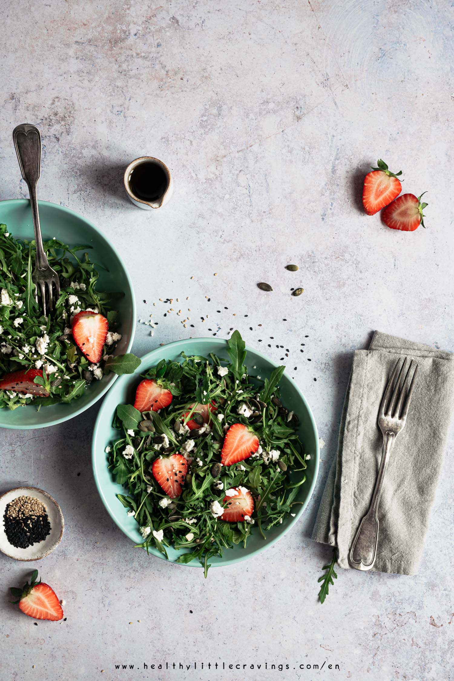 Two plates with arugula salad and napkin on the side