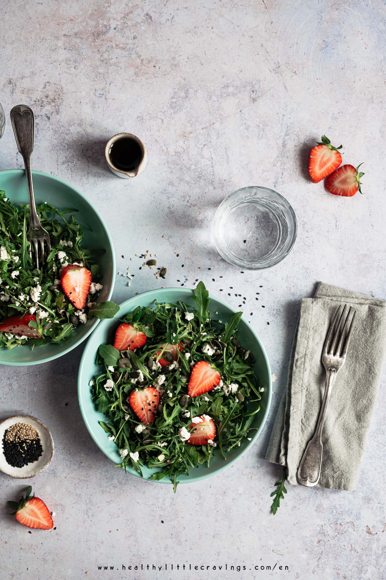 Two bowls of strawberry salad with arugula and feta