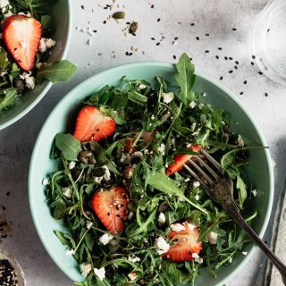 Close up photo of a bowl of strawberry salad with feta and arugula