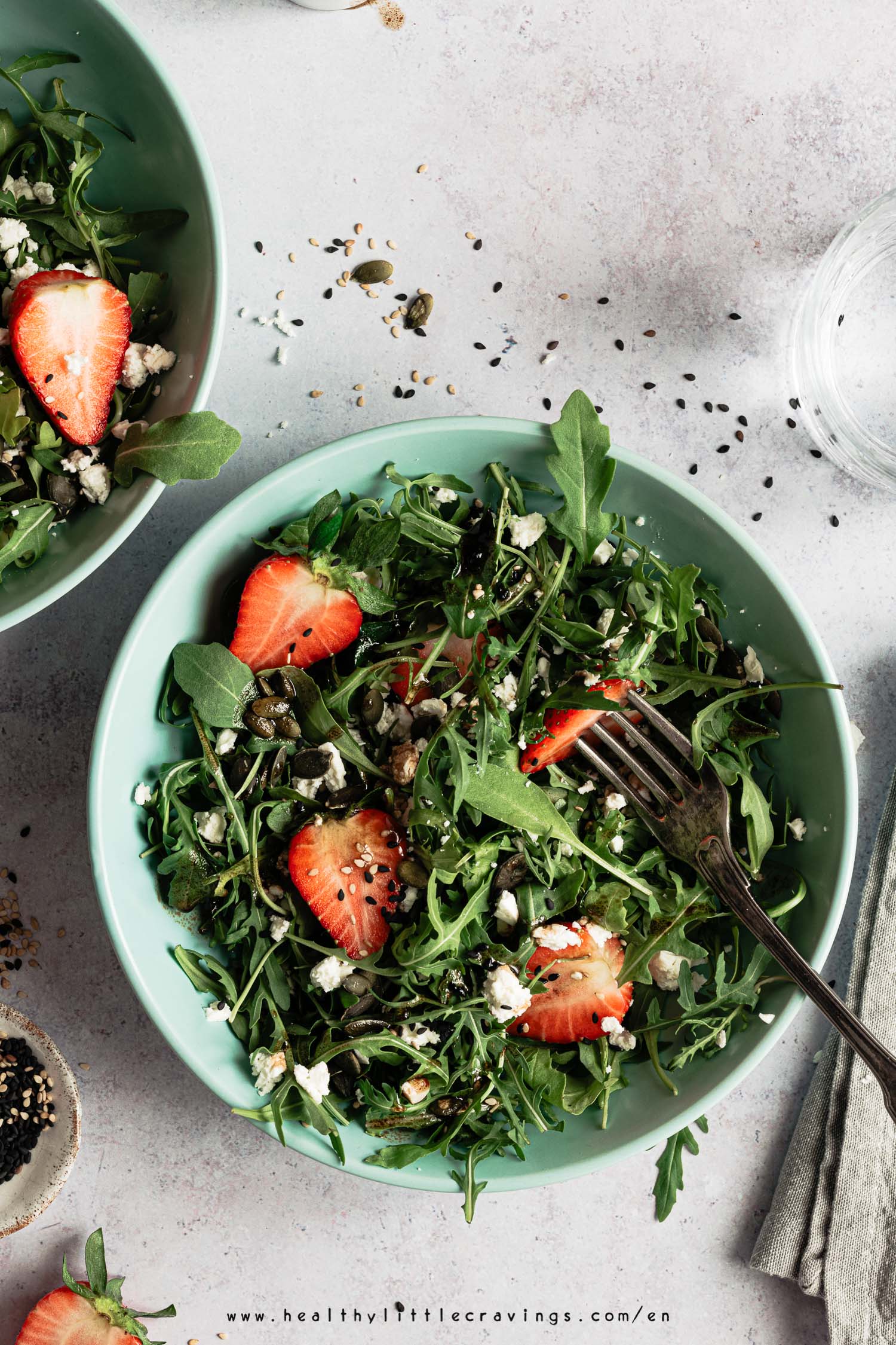 Close up photo of a bowl of salad with arugula, feta and strawberries 