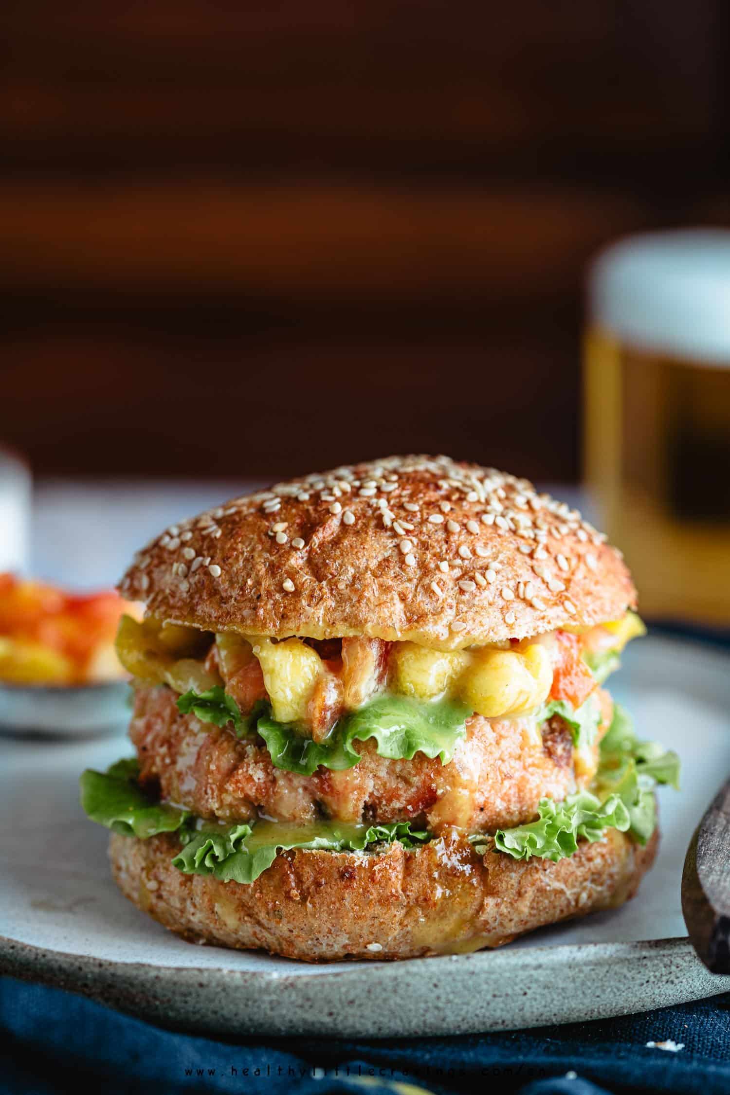 A closeup photo of grilled salmon burgers on a plate with toppings for salmon