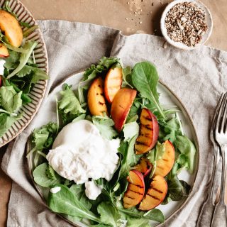 Grilled peach salad on a ceramic plate onto a napkin