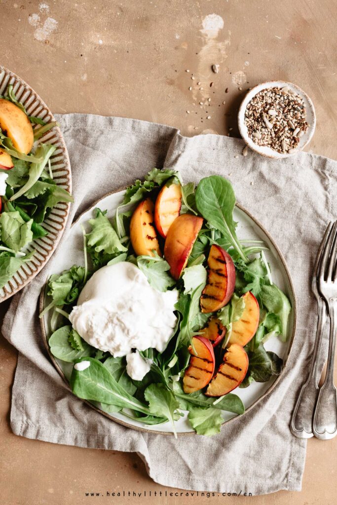 Grilled peach salad on a ceramic plate onto a napkin