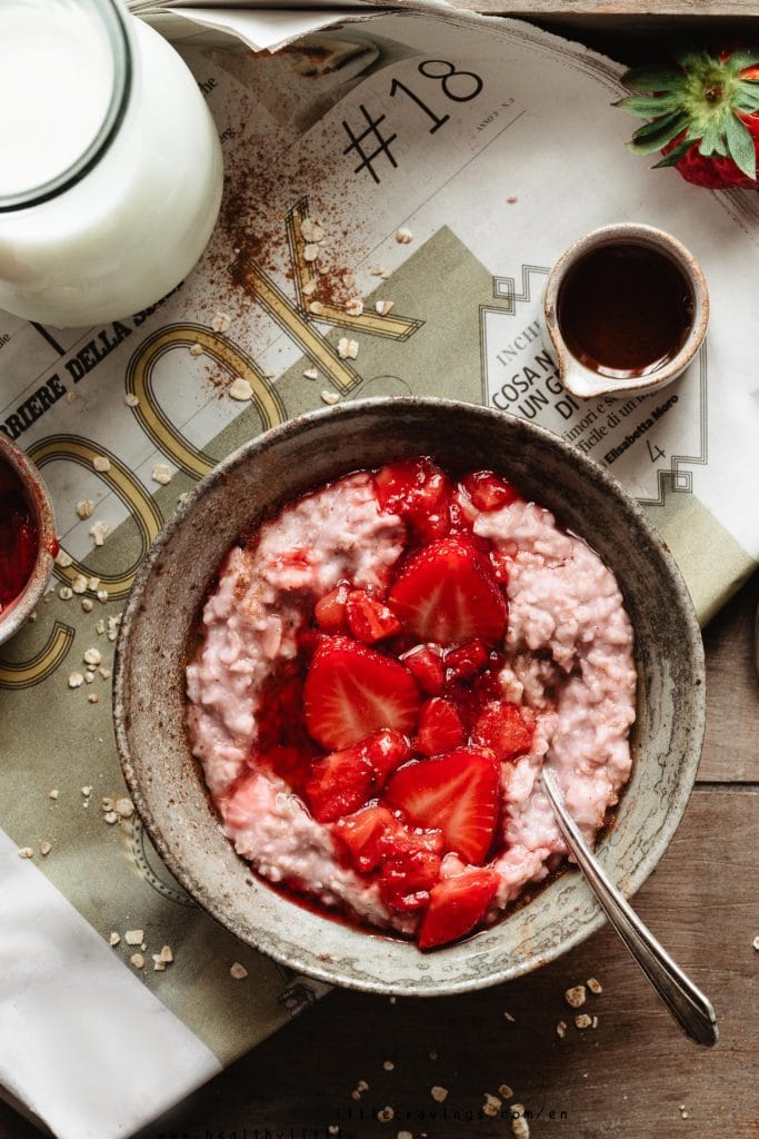 A bowl of Vanilla strawberry oatmeal on a newspaper onto a tray