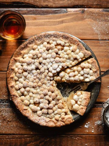 A bourbon pear pie with a glass of the bourbon on the side.