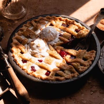 Sour cherry pie with melting ice cream, in sun light.