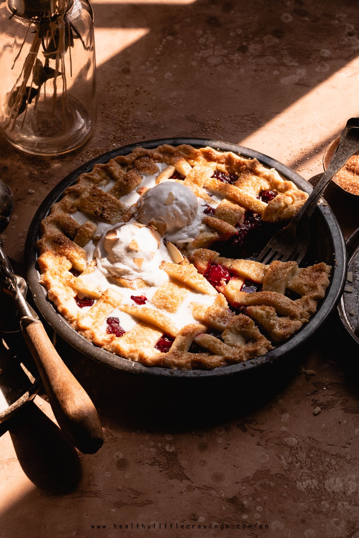 Sour cherry pie with melting ice cream, in sun light.