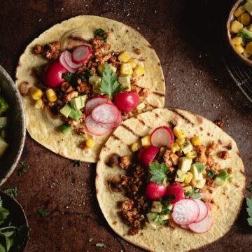 Two tofu tacos served with radishes, avocado and parsley.