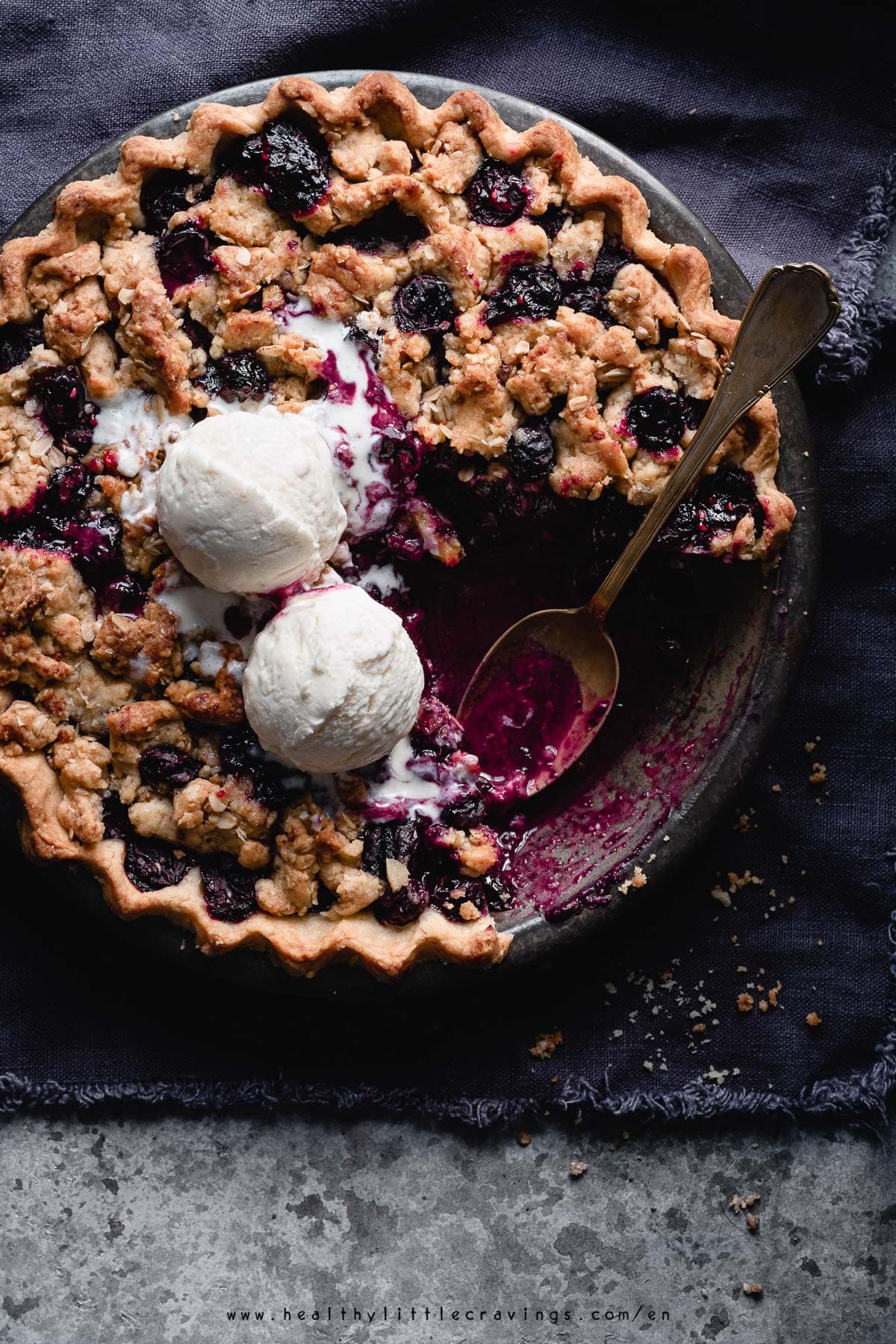 Blueberry crumble pie with vanilla ice cream on top.
